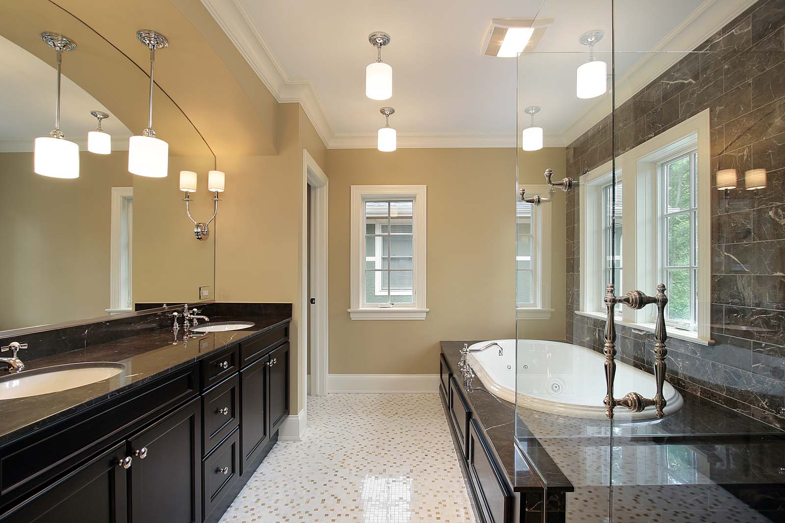 Modern bathroom with dual sinks, dark cabinets, and a large mirror. A corner bathtub and a glass partition separate the shower area. Beige walls and tiled floor enhance the room's elegance, making it a prime example of bathroom remodeling sophistication.