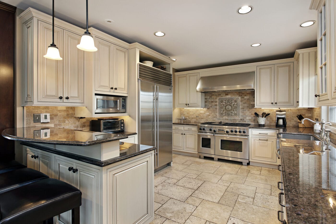 Spacious kitchen with stainless steel appliances, beige cabinets, granite countertops, tile flooring, and hanging pendant lights—perfect for inspiring your next bathroom remodeling project.
